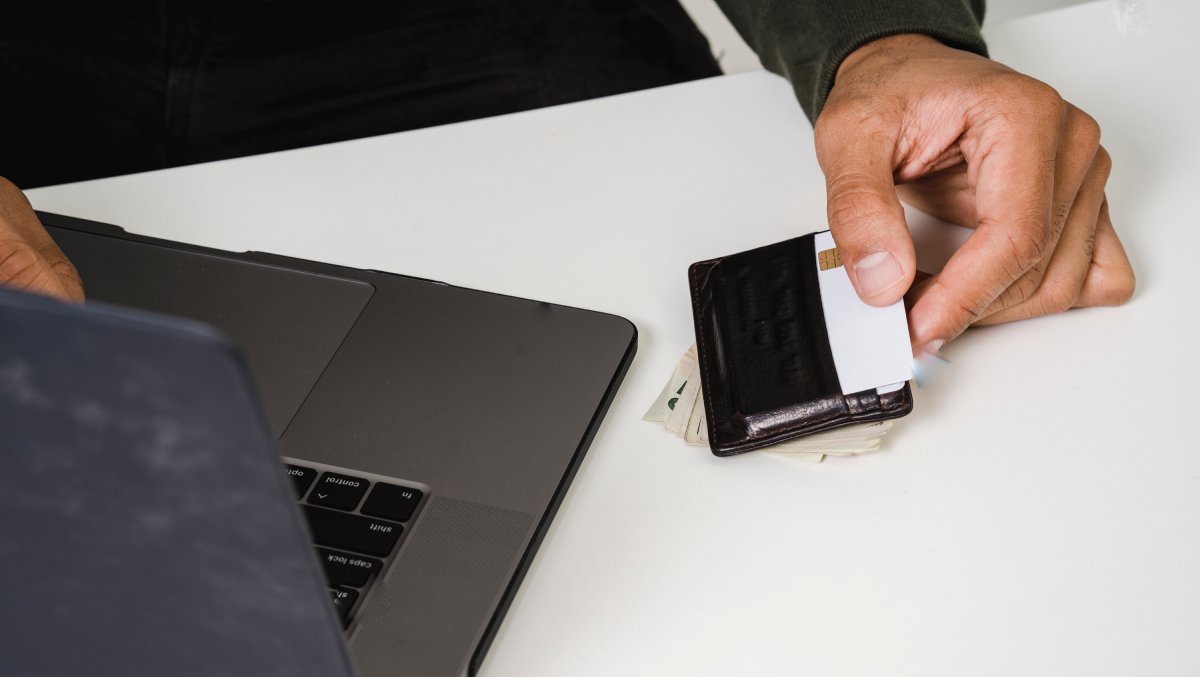 monnaie numérique : personne qui tient une carte bancaire dans les mains devant un ordinateur