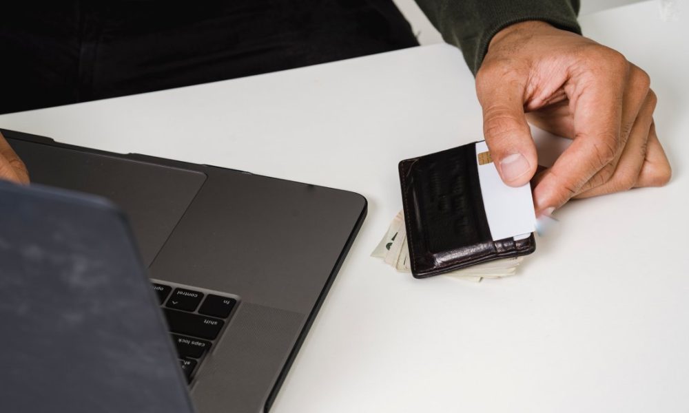 monnaie numérique : personne qui tient une carte bancaire dans les mains devant un ordinateur